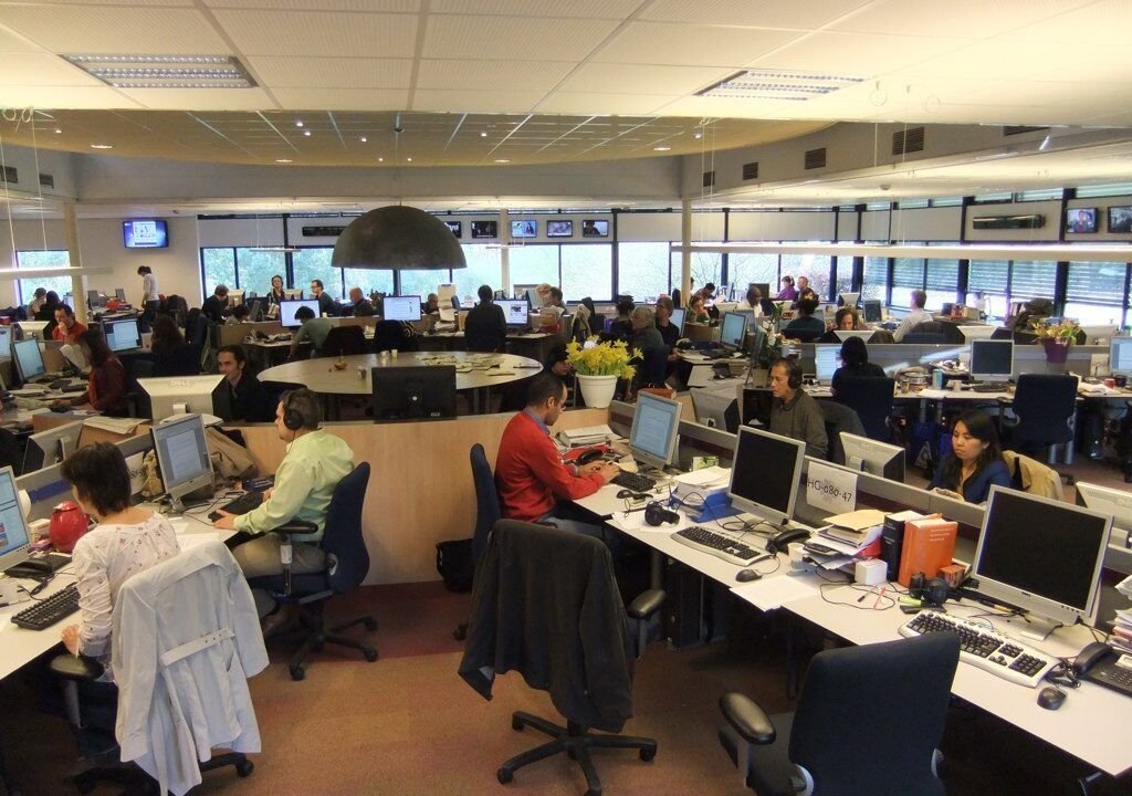 Editors at work around the central desk of a modern newsroom