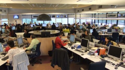 Editors at work around the central desk of a modern newsroom