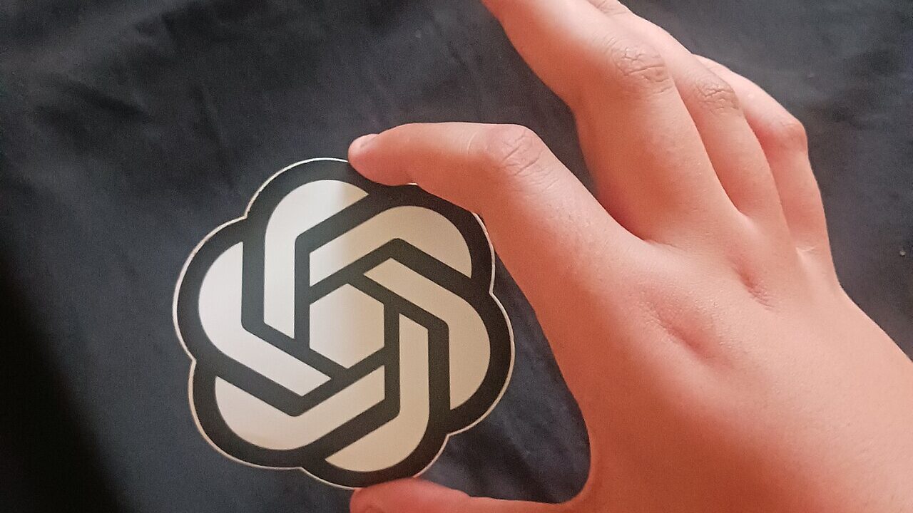 A person holding a printed OpenAI logo icon